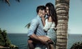 Portrait of attractive lovers leaning on a palm tree Royalty Free Stock Photo