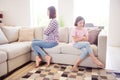 Portrait of two attractive offended girls sitting on divan bad mood fight crossed hands at home flat indoors