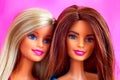 Portrait of two Barbie dolls against pink background