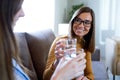 Two beautiful happy women toasting with a glass of water at home.