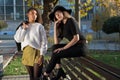 Portrait of two beautiful mexican millennial generation girls. Autumn fashion photo shoot in the park by the bench