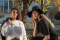 Portrait of two beautiful mexican millennial generation girls. Autumn fashion photo shoot in the park by the bench.