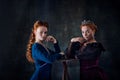 Portrait of two beautiful women in image of queen and princess isolated over dark background. Royal family Royalty Free Stock Photo