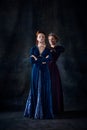 Portrait of two beautiful women in image of queens isolated over dark background. Royal competition for the throne Royalty Free Stock Photo