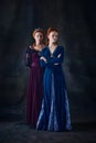 Portrait of two beautiful women in image of queens isolated over dark background. Royal family portrait Royalty Free Stock Photo