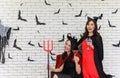 Portrait of two beautiful young asian woman in witch halloween costume on white brick background decorated with black paper bat Royalty Free Stock Photo