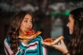 Portrait of two beautiful young women talking and eating pizza outdoors Royalty Free Stock Photo