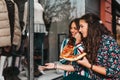 Portrait of two beautiful young women talking and eating pizza outdoors, and pointing finger in the shop window Royalty Free Stock Photo