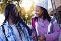 Two beautiful young woman using mobile phone in the street. Royalty Free Stock Photo