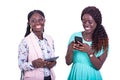 Two beautiful young women using a mobile phone together while smiling Royalty Free Stock Photo