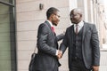 Portrait of two black African American businessman in suits shake hands outdoors. The joy of meeting good friends Royalty Free Stock Photo