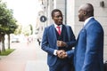 Portrait of two black African American businessman in suits shake hands outdoors. The joy of meeting good friends Royalty Free Stock Photo