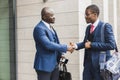 Portrait of two black African American businessman in suits shake hands outdoors. The joy of meeting good friends Royalty Free Stock Photo