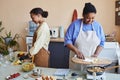 Two black young women preparing meals together cooking in kitchen Royalty Free Stock Photo