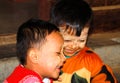 Portrait of two burmese happy male children boys with traditional thanaka face painting playing in front of their hut