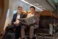 Businessman in brown suit on trip holding business newspaper while reading in plane during flight Royalty Free Stock Photo