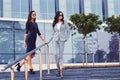 Portrait of two businesswomen dressed in a stylish formal clothes, standing on steps posing against a background of a Royalty Free Stock Photo