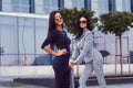 Portrait of two businesswomen dressed in a stylish formal clothes, standing on steps posing against a background of a Royalty Free Stock Photo