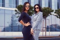 Portrait of two businesswomen dressed in a stylish formal clothes, standing on steps posing against a background of a Royalty Free Stock Photo