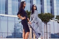 Portrait of two businesswomen dressed in a stylish formal clothes, standing on steps posing against a background of a Royalty Free Stock Photo