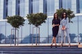 Portrait of two businesswomen dressed in a stylish formal clothes, standing on steps posing against a background of a Royalty Free Stock Photo