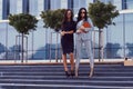 Portrait of two businesswomen dressed in a stylish formal clothes, standing on steps posing against a background of a Royalty Free Stock Photo