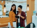 Portrait of two businesswomen talking to each other while standing in a modern business office with their colleagues Royalty Free Stock Photo