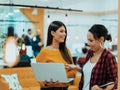 Portrait of two businesswomen talking to each other while standing in a modern business office with their colleagues Royalty Free Stock Photo