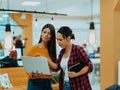 Portrait of two businesswomen talking to each other while standing in a modern business office with their colleagues Royalty Free Stock Photo