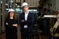 Portrait of two Caucasian engineers standing beside welding robot machine arm in mechanic factory