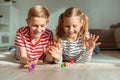 Portrait of two cheerful children laying on the floor and playing with colorful dices Royalty Free Stock Photo