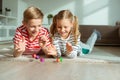 Portrait of two cheerful children laying on the floor and playing with colorful dices Royalty Free Stock Photo