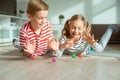 Portrait of two cheerful children laying on the floor and playing with colorful dices Royalty Free Stock Photo