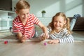 Portrait of two cheerful children laying on the floor and playing with colorful dices Royalty Free Stock Photo