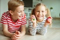 Portrait of two cheerful children laying on the floor and playing with colorful dices Royalty Free Stock Photo