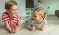 Portrait of two cheerful children laying on the floor and playing with colorful dices Royalty Free Stock Photo