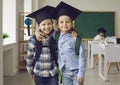 Portrait of two cheerful little school boys in mortar boards who are best friends in class. Royalty Free Stock Photo