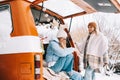 Portrait of two cheerful women friends sitting in a van in winter camp, enjoying holiday Royalty Free Stock Photo