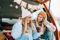 Portrait of two cheerful women friends sitting in a van in winter camp and having fun, enjoying holiday Royalty Free Stock Photo