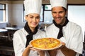 Portrait of two chef presenting a pizza Royalty Free Stock Photo