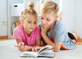 Portrait of two children reading a book on the floor at home Royalty Free Stock Photo