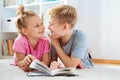 Portrait of two children reading a book on the floor at home Royalty Free Stock Photo
