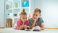 Portrait of two children reading a book on the floor at home Royalty Free Stock Photo