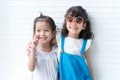 Portrait of two cute Asian and Caucasian little girls as friends hug each other, smiling, posing in studio white background. Royalty Free Stock Photo