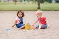 Two cute Caucasian and hispanic latin toddlers babies children sitting in sandbox playing with plastic colorful toys Royalty Free Stock Photo