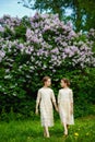 Portrait of two cute girls hugging each other in identical dresses. Two sisters in the park on the background of lilac Royalty Free Stock Photo