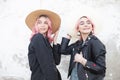 Portrait two cute happy girlfriends in trendy casual clothes in straw vintage hats near a white wall in city. Fashion attractive Royalty Free Stock Photo