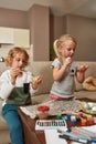 Portrait of two cute little children, brother and sister looking focused while painting colorful Easter eggs, sitting on Royalty Free Stock Photo