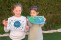 Portrait of the two cute little girls holding the drawing earth globe.Kids paintig picture of earth having fun outdoor.