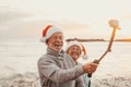 Portrait of two cute old persons having fun and enjoying together at the beach on christmas days at the beach wearing Christmas Royalty Free Stock Photo
